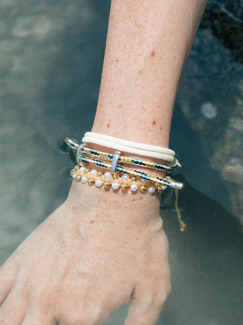 Hand with multiple bracelets on a blurred natural background
